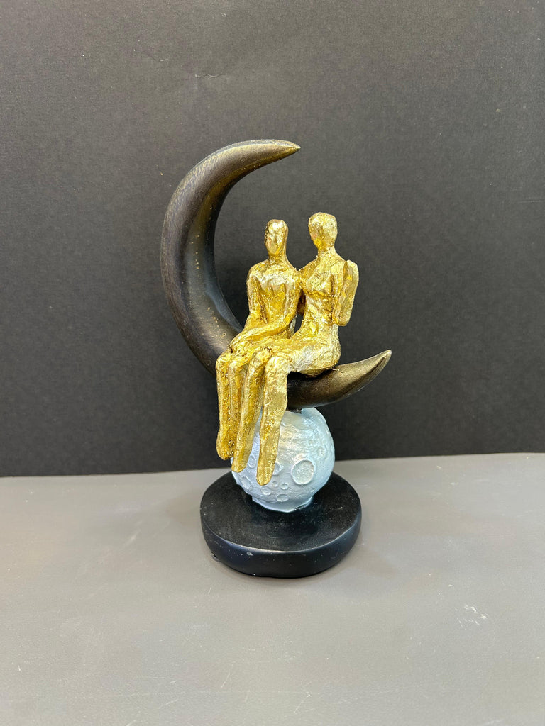 Couple Sitting on Moon Shaped Artefact For Home Decor