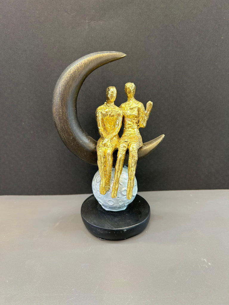 Couple Sitting on Moon Shaped Artefact For Home Decor