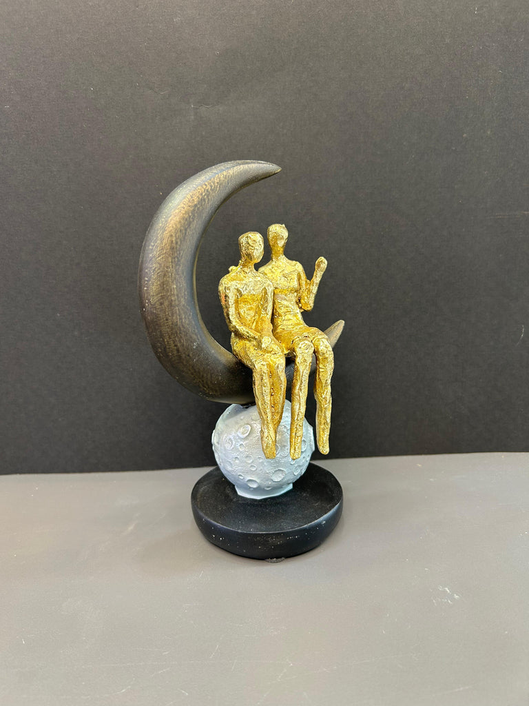 Couple Sitting on Moon Shaped Artefact For Home Decor